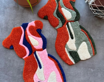 以下が含まれることがあります： カラフルな渦巻き模様の抽象的な形のラグ2枚。ラグは柔らかく、ふわふわした素材でできており、オレンジ、ピンク、グリーン、ブルー、ホワイトの色合いが特徴です。
