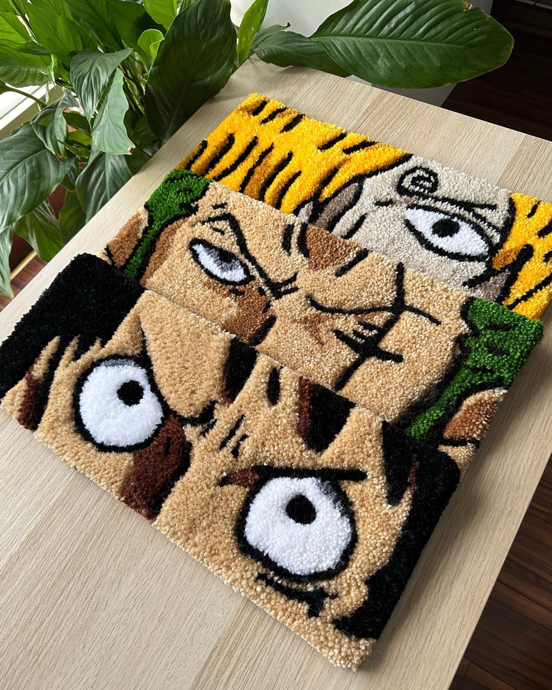 May include: Three colorful rug-like wall hangings with cartoon faces. The top rug is beige with a yellow face, the middle rug is green and beige with a brown face, and the bottom rug is brown with a black face.
