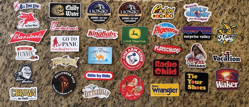 May include: A collection of various rectangular, circular, and die-cut vinyl stickers featuring diverse graphic designs, logos, and text including phrases like Chilly Water, Honky Shed, KingBaby, Love Tractor, Radio Child, and The Waker.