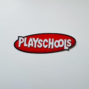 May include: A flat, oval-shaped sign featuring a vibrant red background with a thick black border. The word PLAYSCHOOLS is written across the center in bold, white, sans-serif capital letters with a slight drop shadow effect.