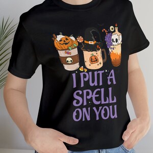 May include: Black t-shirt with a graphic of three Halloween-themed mugs with the text "I put a spell on you".