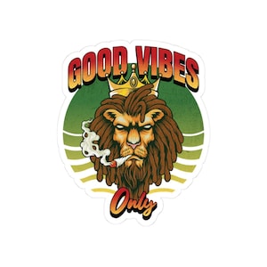 May include: A sticker featuring a lion with dreadlocks wearing a crown and smoking a cigarette. The words "GOOD VIBES ONLY" are written above and below the lion in a stylized font. The background is a green and yellow striped circle.