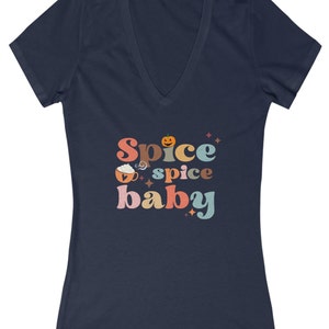 Può includere: Una t-shirt blu navy a collo a V con il testo "Spice spice baby" in un font retrò con una zucca e una tazza di caffè con panna montata.