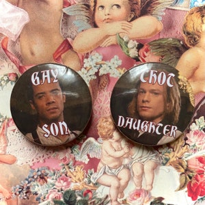 May include: Two round buttons with images of people and text. The left button has a photo of a person with brown hair and brown eyes, and the text "gay son". The right button has a photo of a person with blonde hair and blue eyes, and the text "s/o's daughter".