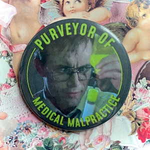 Puede incluir: Una insignia de botón en blanco y negro con el texto "Purveyor of Medical Malpractice" en un círculo blanco. El texto está en negrita, en blanco. Un hombre con gafas aparece en el centro de la insignia.
