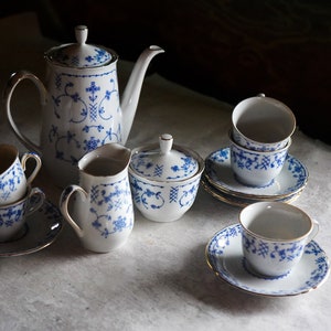 Op de afbeelding: Een blauw en wit porseleinen theeservies met een theepot, roomkan, suikerpot en vier kopjes en schoteltjes.