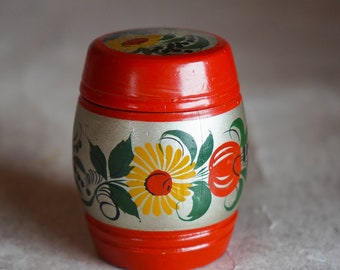 May include: A small, red wooden barrel with a silver band and painted floral designs. The flowers are yellow with red centers and green leaves.