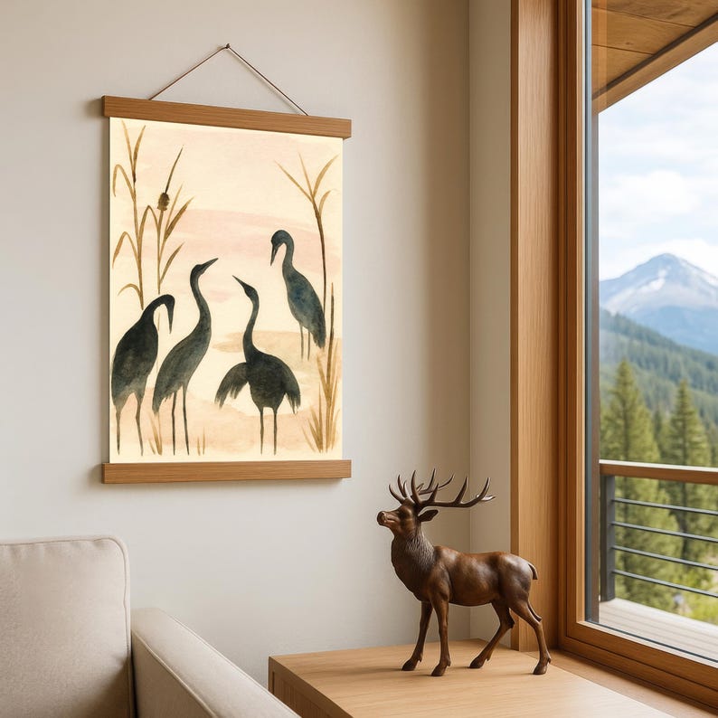 May include: A framed watercolor print featuring five dark blue herons in a marsh setting. The artwork is displayed with a wooden frame and hanging cord. A bronze deer statue stands on a wooden table.