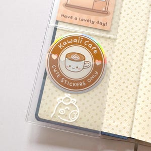 Op de afbeelding: Een holografische sticker met een schattig cartoon-koffiekopje en de tekst "Kawaii Cafe Cute Stickers Only".