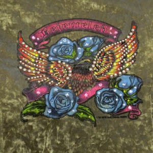 May include: An olive green velvet fabric featuring a graphic print of an eagle with outstretched wings, blue roses, and a pink banner with the text Bejeweled. The design is embellished with numerous small white, yellow, and red rhinestones.