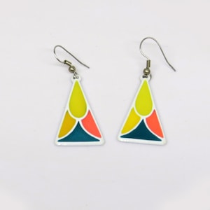 May include: A pair of colorful triangle earrings. Each earring has a white border and is filled with yellow, orange, teal, and gold sections. The earrings have silver-colored fish hook ear wires.