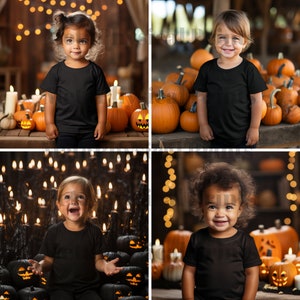 May include: Four children wearing black t-shirts pose in front of Halloween decorations. The children are surrounded by pumpkins and candles.