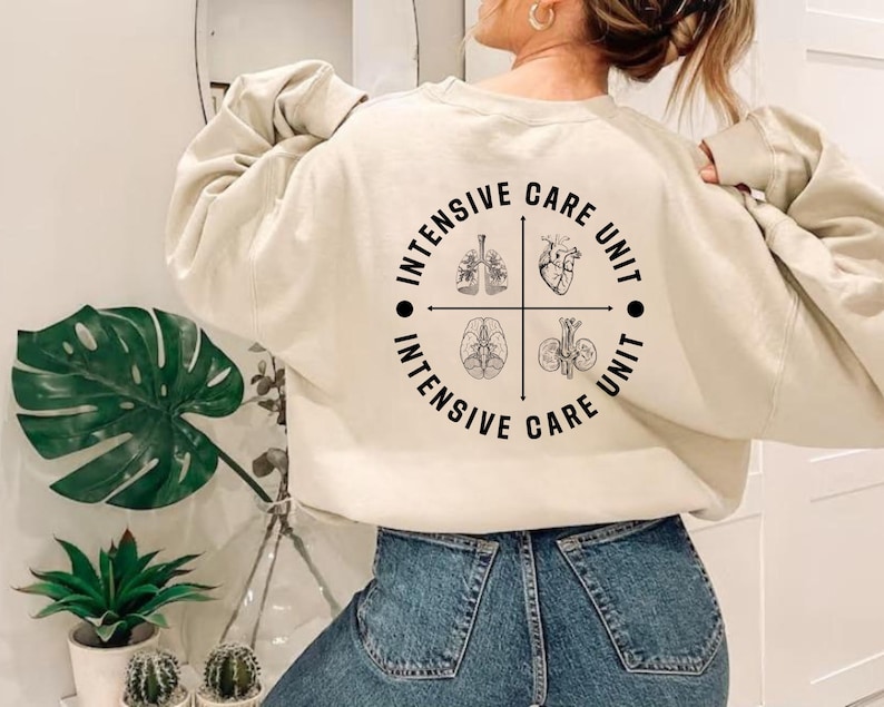 May include: Cream-colored sweatshirt with a circular graphic on the back. The graphic features anatomical illustrations of the lungs, heart, brain, and kidneys, with the words "INTENSIVE CARE UNIT" encircling the images.