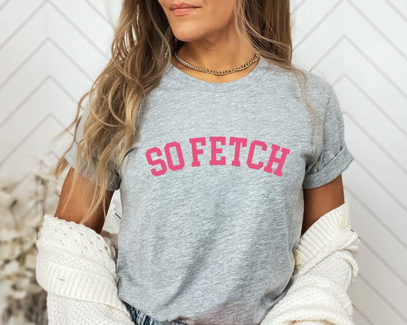 Op de afbeelding: Grijs T-shirt met de tekst "SO FETCH" in roze letters.