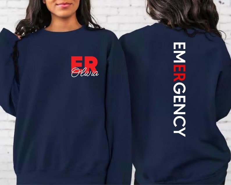 May include: Navy blue sweatshirt with the text "ER Olivia" in red on the front and "EMERGENCY" in white on the back.