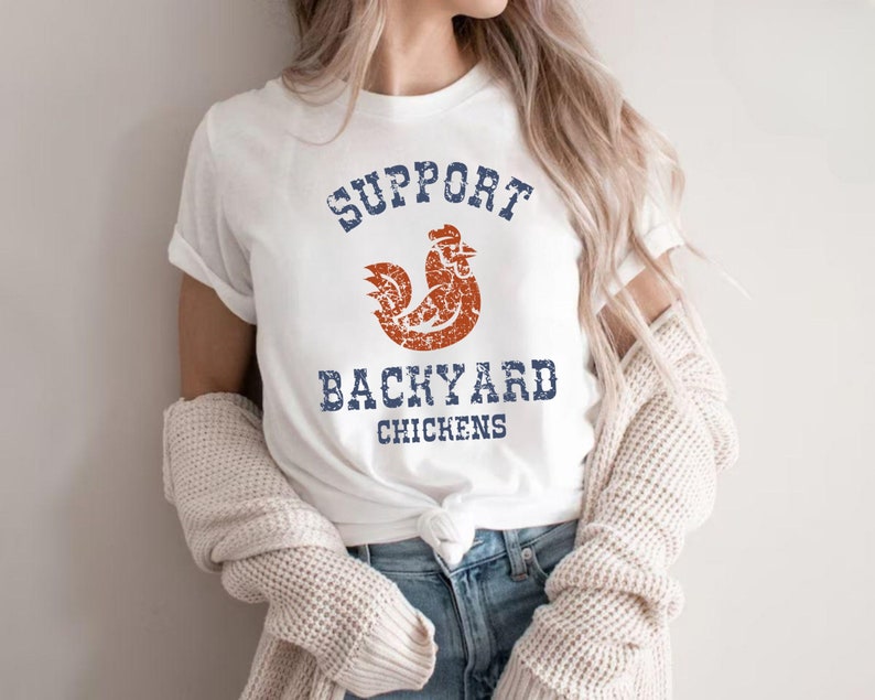 May include: White t-shirt with a distressed blue and red graphic that says "Support Backyard Chickens".