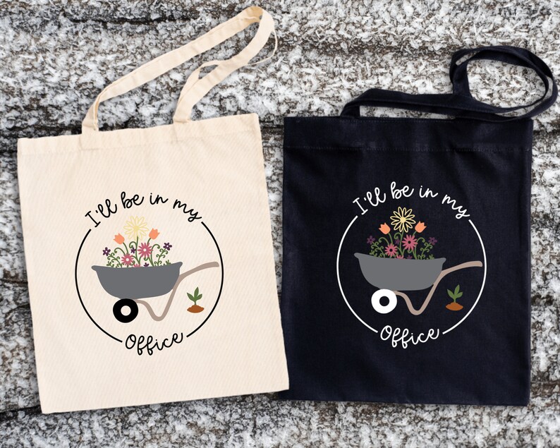 May include: Two tote bags with a white background and a black background. Both bags have a graphic of a wheelbarrow filled with flowers and the text "I'll be in my office".