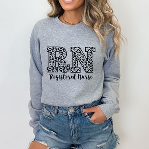May include: A gray sweatshirt with a leopard print "RN" design and the text "Registered Nurse" below.