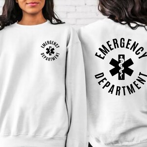 May include: White sweatshirt with a black graphic on the front and back. The graphic is a circle with the text "EMERGENCY DEPARTMENT" and a medical symbol with a snake.