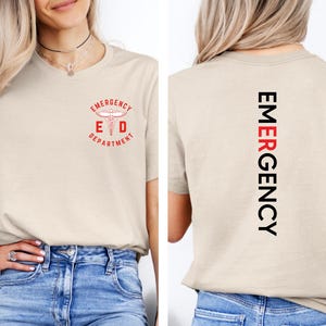 Puede incluir: Camiseta beige con un dise&ntilde;o rojo y negro. La parte delantera de la camiseta presenta el texto "Emergency Department" con un s&iacute;mbolo m&eacute;dico. La parte trasera de la camiseta tiene la palabra "EMERGENCY" impresa verticalmente en negro y rojo.