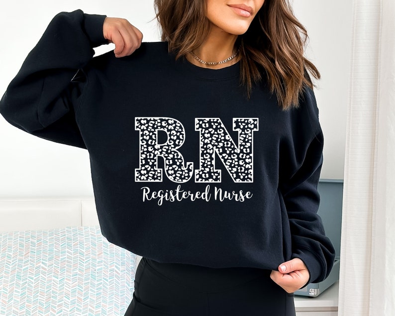 May include: Black sweatshirt with a white leopard print "RN" design and the text "Registered Nurse" below.