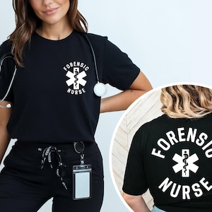 May include: A black short-sleeved t-shirt featuring a white graphic on the chest and back. The graphic displays a Star of Life symbol with a serpent and staff, surrounded by the text "FORENSIC NURSE" in a bold, white, sans-serif font.