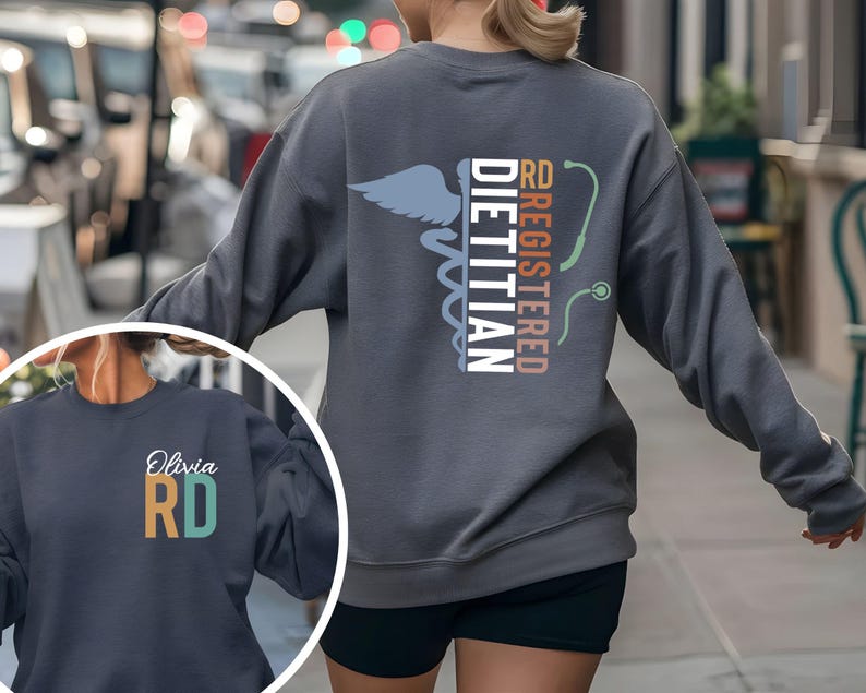 May include: A gray sweatshirt featuring the text "RD REGISTERED DIETITIAN" with a caduceus symbol and a stethoscope graphic. The sweatshirt also has a smaller image with the name "Olivia" and the letters "RD".