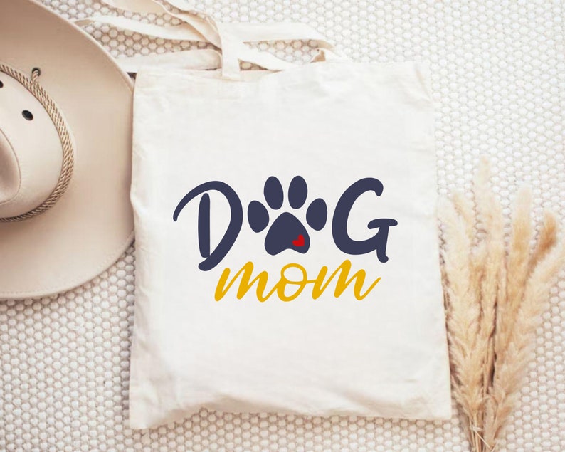 May include: White canvas tote bag with a blue paw print and the text "Dog Mom" in yellow.