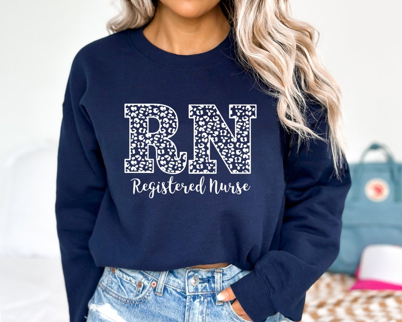May include: A navy blue sweatshirt with a white leopard print "RN" design and the text "Registered Nurse" below.