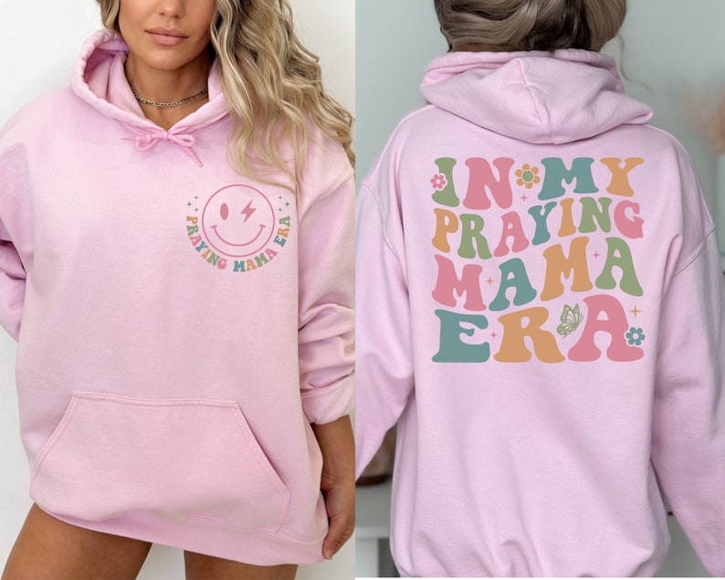 May include: Pink hoodie with a smiley face and the text "Praying Mama Era" on the front and the text "In My Praying Mama Era" on the back.