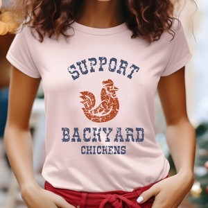 May include: A pink t-shirt with a distressed blue and white graphic that says "Support Backyard Chickens" with a distressed orange rooster graphic.