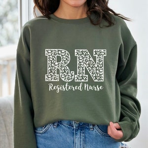 May include: A green sweatshirt with a white leopard print "RN Registered Nurse" design.