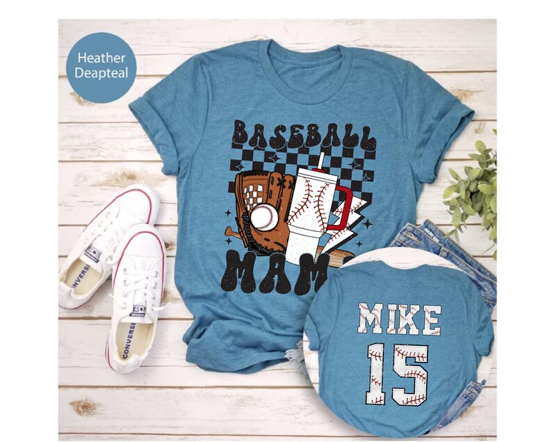 May include: A teal t-shirt with a baseball-themed graphic that says "Baseball Mama." The design includes a baseball glove, a baseball, and a drink with a baseball design. A second shirt shows "Mike 15" on the back. White sneakers are visible.