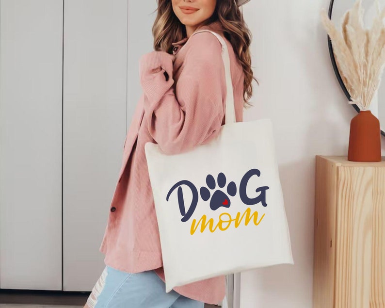 May include: A white tote bag with a blue paw print and the text "Dog Mom" in yellow letters.