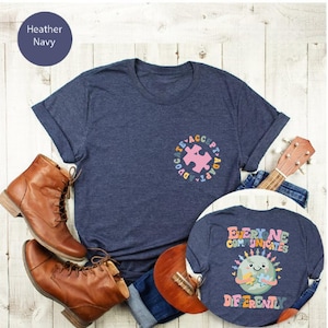 May include: Two navy blue t-shirts with autism awareness designs. The larger shirt has a puzzle piece with the words "Advocate, Accept, Adapt" around it. The smaller shirt has a cartoon earth with the words "Everyone Communicates Differently".