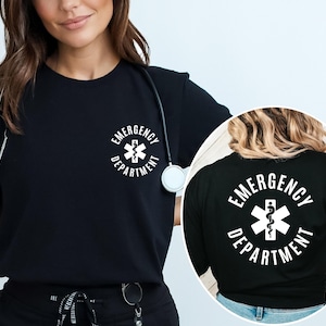 May include: A black short-sleeved t-shirt featuring a white graphic on the chest and back. The graphic displays the text EMERGENCY DEPARTMENT in a circular arrangement surrounding a white Star of Life medical symbol with a central serpent staff.