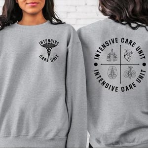 May include: A gray sweatshirt with the words "Intensive Care Unit" and a medical symbol on the front. The back of the sweatshirt features a circular design with the words "Intensive Care Unit" and illustrations of internal organs.