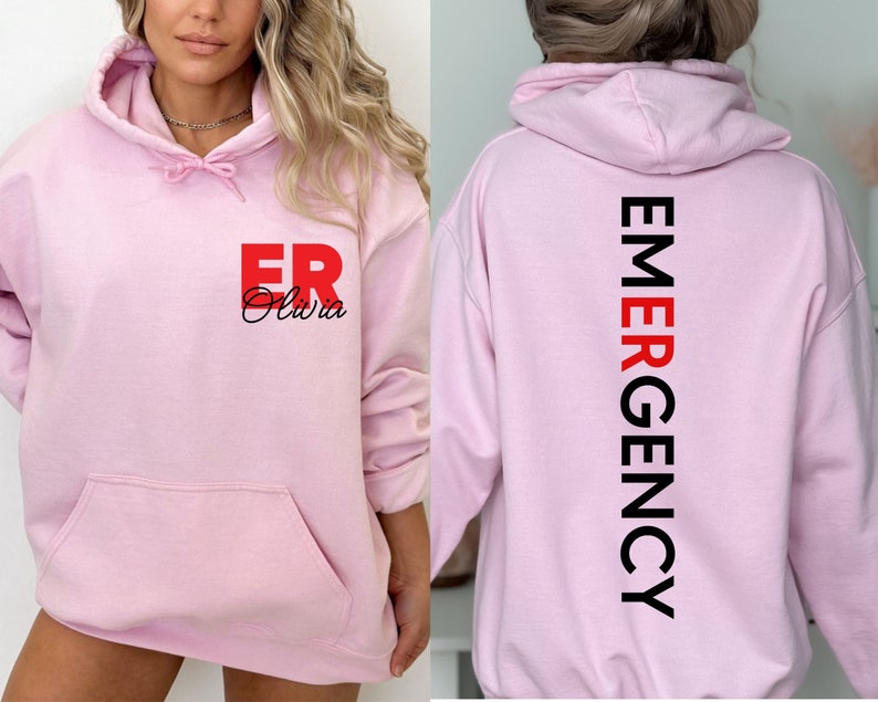 May include: Pink hoodie with the text "ER Olivia" on the front and "EMERGENCY" vertically down the back.