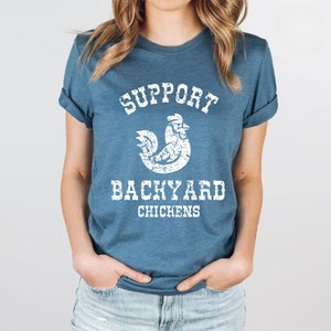 May include: A blue t-shirt with a white distressed graphic of a chicken and the text "Support Backyard Chickens".
