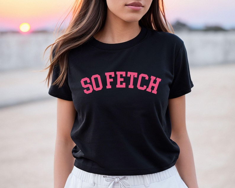 Op de afbeelding: Zwart gecropped T-shirt met een roze "SO FETCH" print.