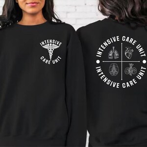 May include: Black sweatshirt with white text and medical symbol. The front displays "Intensive Care Unit" with a caduceus. The back features a circular design with "Intensive Care Unit" and illustrations of internal organs.