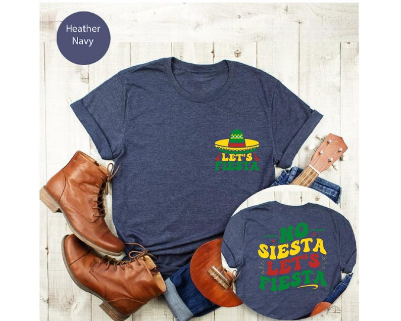 May include: Two navy blue t-shirts with a fiesta theme. The larger shirt has a green, red, and yellow sombrero with the text "Let's Fiesta". The smaller shirt has the text "No Siesta Let's Fiesta".