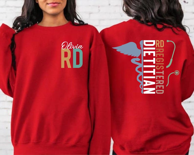 May include: Red sweatshirt with the text "Olivia RD" on the front. The back of the sweatshirt features the words "RD Registered Dietitian" with a caduceus and stethoscope graphic. The sweatshirt is a solid red color.