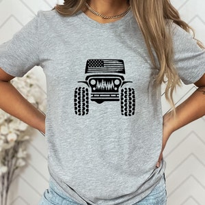 May include: A gray t-shirt with a black graphic of a Jeep with an American flag on the hood.