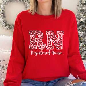 May include: Red sweatshirt with a white leopard print "RN Registered Nurse" design.