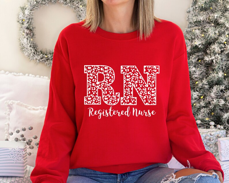 May include: Red sweatshirt with a white leopard print "RN Registered Nurse" design.