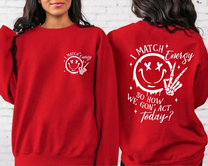 Puede incluir: Sudadera roja con un estampado gr&aacute;fico blanco de una cara sonriente con los ojos cruzados y una mano de esqueleto haciendo el signo de la paz. El texto dice "I Match Energy So How We Gon' Act Today?"