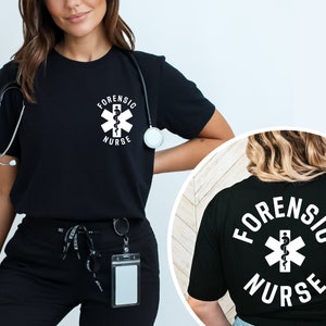 May include: Black t-shirt with white text that reads "Forensic Nurse" and a white medical symbol with a snake. The back of the shirt has the same text and symbol.