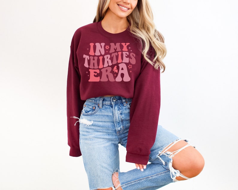 May include: A maroon sweatshirt with a pink and red graphic that says "In My Thirties Era" with stars and flowers around the text.