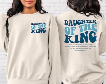 May include: A white sweatshirt with the text "Daughter of the King" in blue and light blue lettering. The back of the sweatshirt has the same text with a bible verse from 2 Corinthians 6:18.